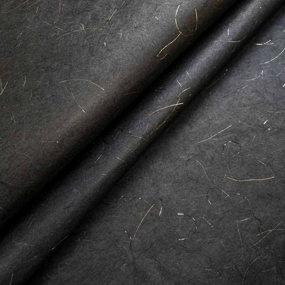 Close-up of Kozo Studio handmade paper in Golden Tinsel Unryu style, featuring a rich black mulberry paper base with delicate gold threads and a softly textured surface.