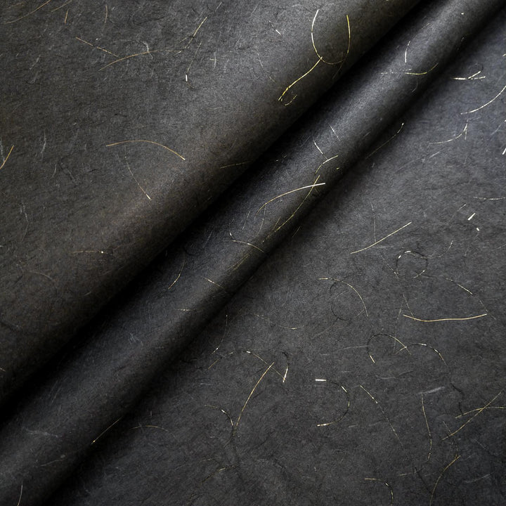 Close-up of Kozo Studio handmade paper in Golden Tinsel Unryu style, featuring a rich black mulberry paper base with delicate gold threads and a softly textured surface.