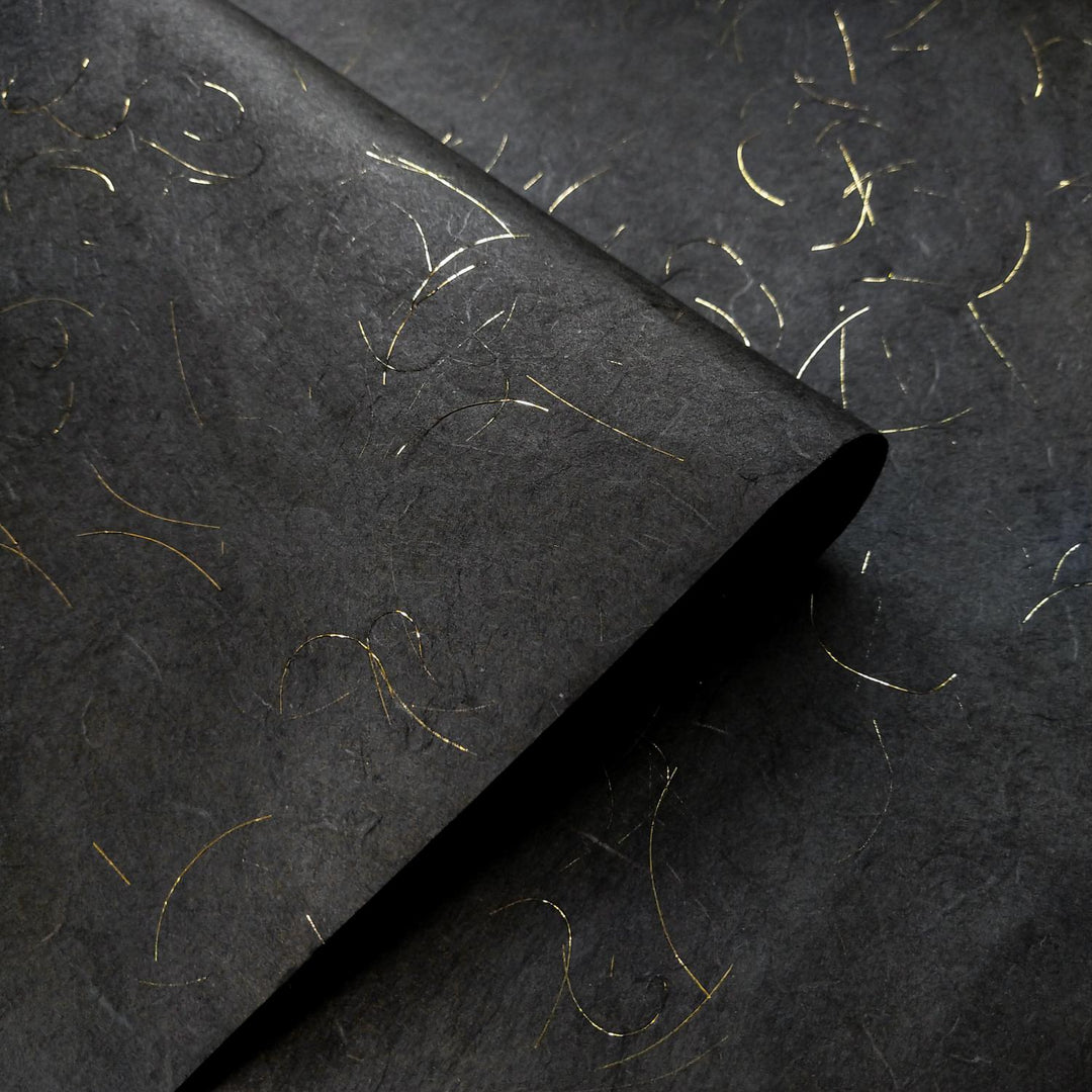 Intricate texture of Kozo Studio black handmade paper, made from mulberry paper with gold tinsel accents woven into the Unryu design.