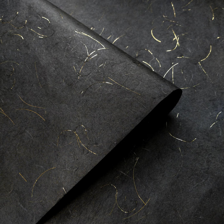 Intricate texture of Kozo Studio black handmade paper, made from mulberry paper with gold tinsel accents woven into the Unryu design.