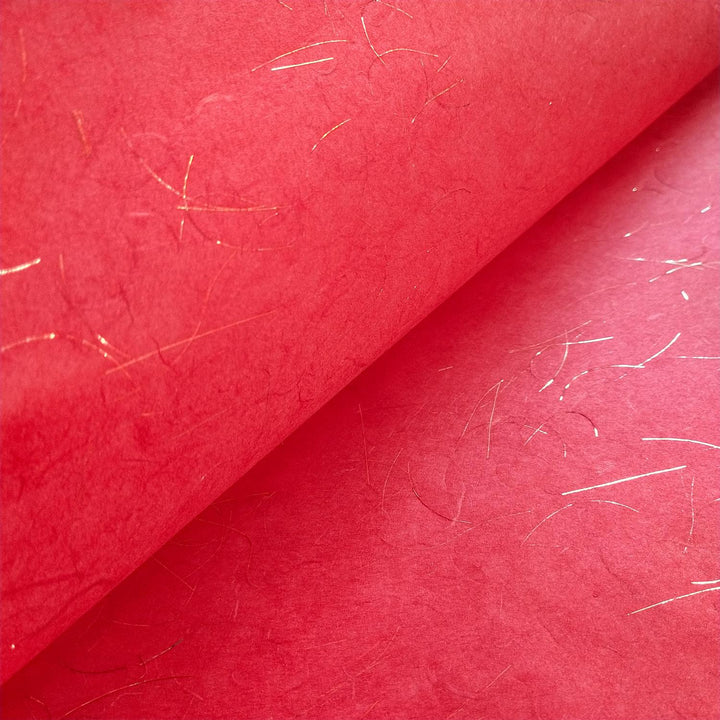 Close-up of Kozo Studios Golden Tinsel Unryu Kozo Paper in Cherry Red, featuring textured mulberry paper interwoven with gold fibers. The folded section showcases its rich color and metallic detailing, reminiscent of traditional rice paper craftsmanship.
