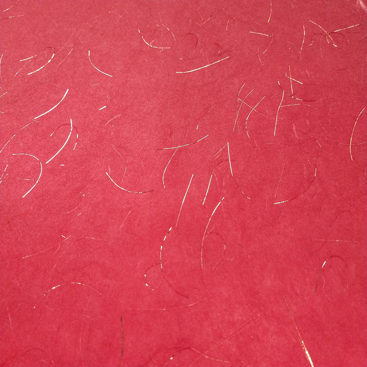 Handmade paper from Kozo Studio made with translucent mulberry fibers and accented with gold tinsel, perfect for artistic projects and decorative wrapping.