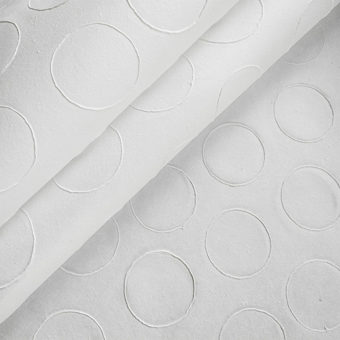 The Handmade Circle Marking Kozo Paper (White) by Kozo Studio features a close-up of textured Mulberry rice paper with embossed circles, creating a subtle, raised design that uniformly covers the surface.