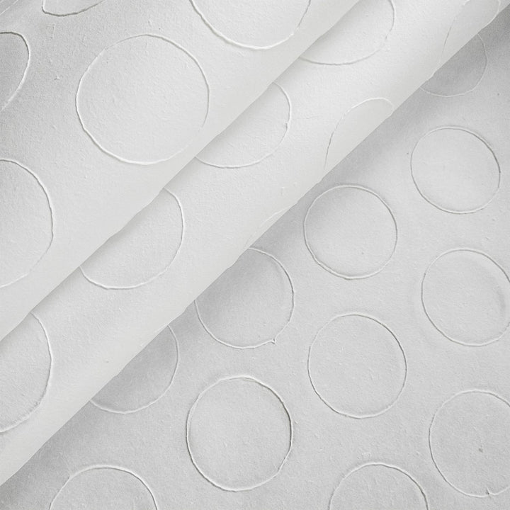 The Handmade Circle Marking Kozo Paper (White) by Kozo Studio features a close-up of textured Mulberry rice paper with embossed circles, creating a subtle, raised design that uniformly covers the surface.