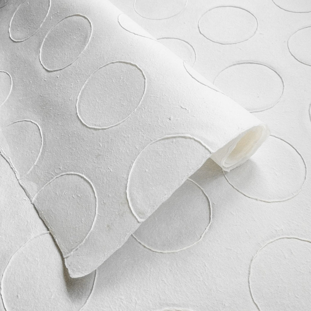 Close-up of handmade mulberry paper from Kozo Studio, featuring raised circle patterns and a soft textured surface perfect for art and decor projects.