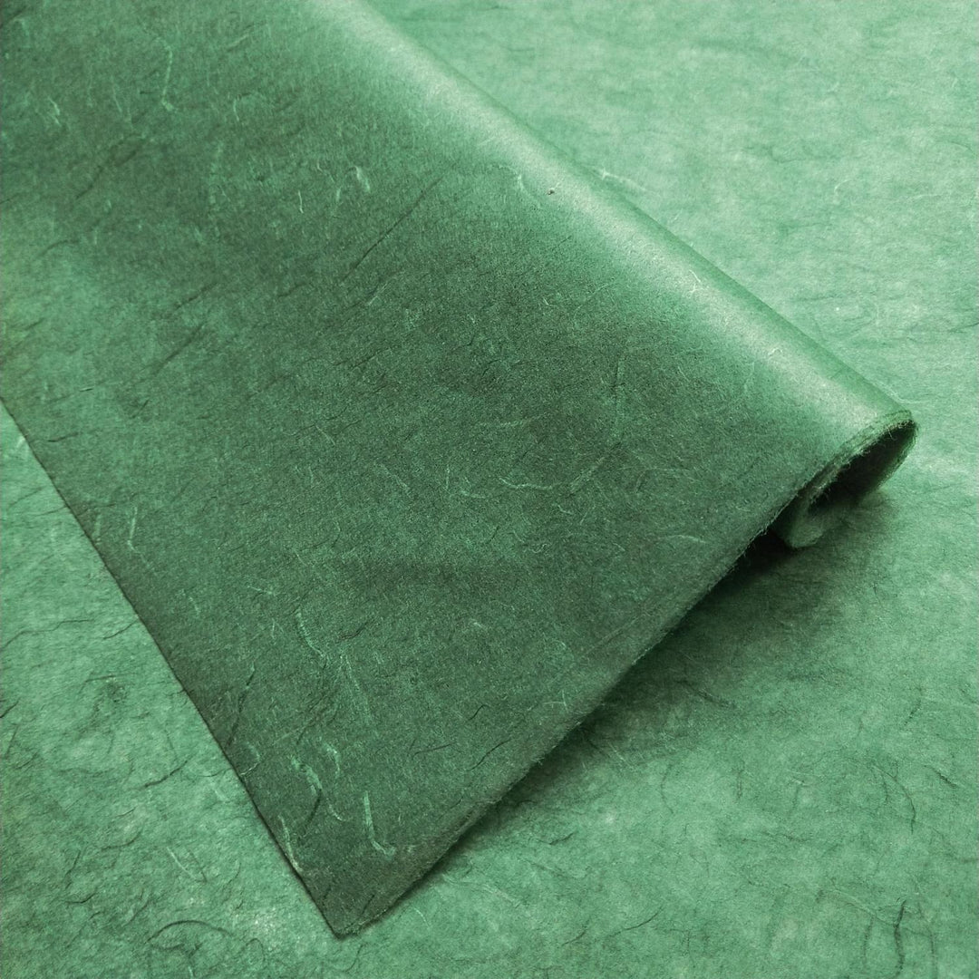 Handmade paper in Amazon Green from Kozo Studio featuring overlapping folds and earthy tones, crafted from traditional mulberry paper with a fibrous texture.