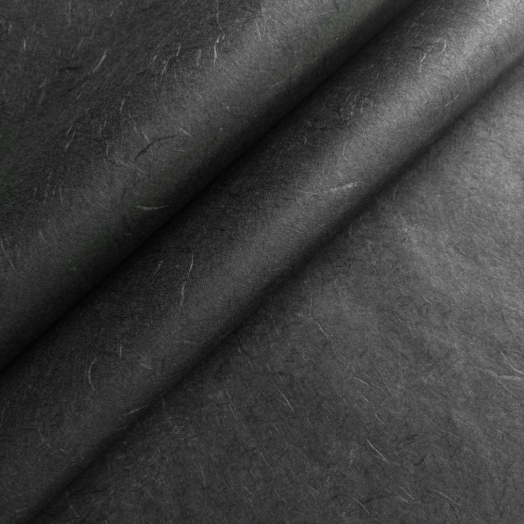 Close-up of black Unryu mulberry paper from Kozo Studio, showcasing the natural texture and layered folds of handmade paper.