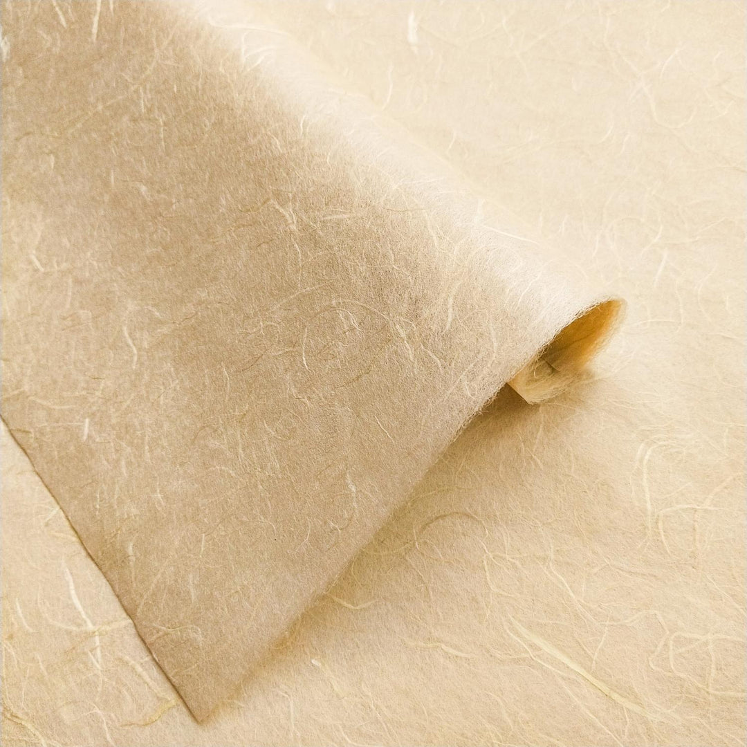 Textured handmade paper sheet in beach sand tone, crafted from mulberry fibers by Kozo Studio, with natural fiber details visible.