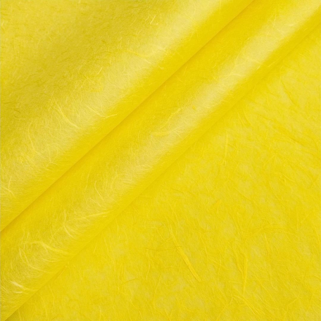 Close-up of handmade mulberry paper in canary yellow by Kozo Studio, highlighting delicate visible fibers and soft texture.