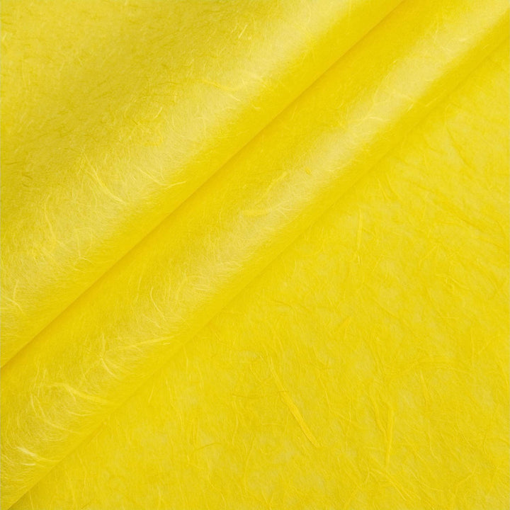Close-up of handmade mulberry paper in canary yellow by Kozo Studio, highlighting delicate visible fibers and soft texture.