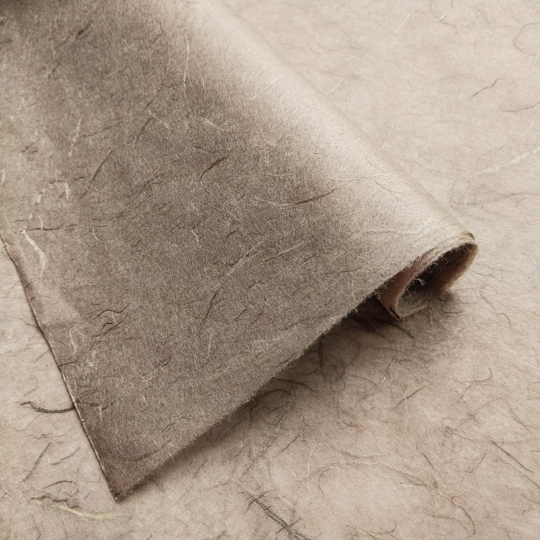 Textured surface of grey handmade paper by Kozo Studio, featuring visible fibers and unique mulberry paper layering.