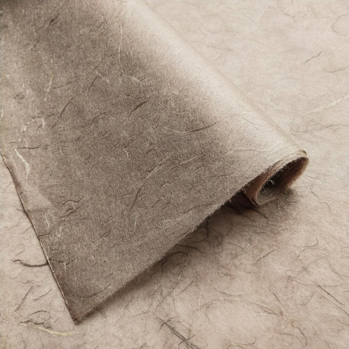 Textured surface of grey handmade paper by Kozo Studio, featuring visible fibers and unique mulberry paper layering.