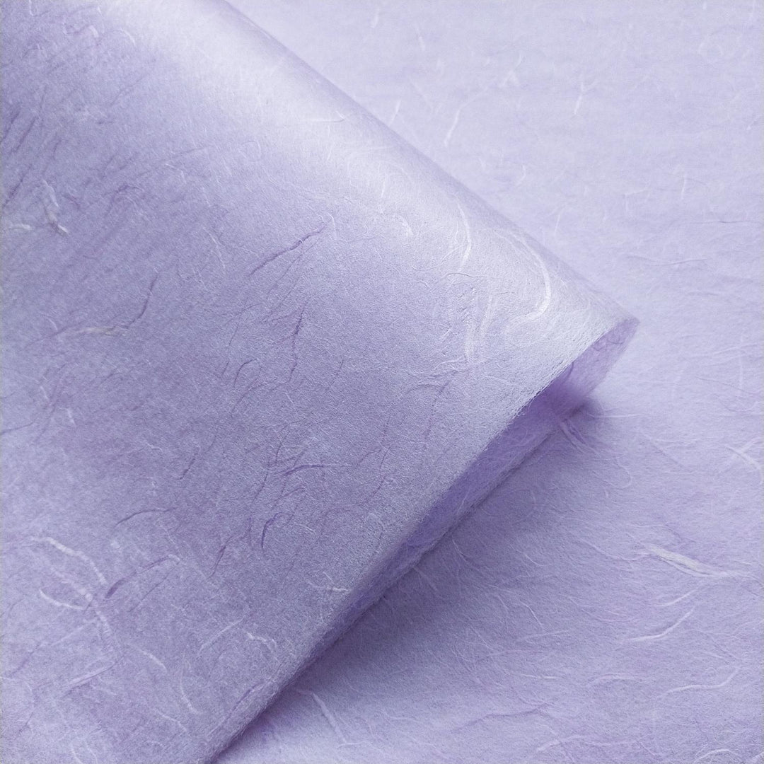 Heather purple mulberry paper from Kozo Studio displayed in overlapping layers, emphasizing the handcrafted quality and fibrous surface of this handmade paper.