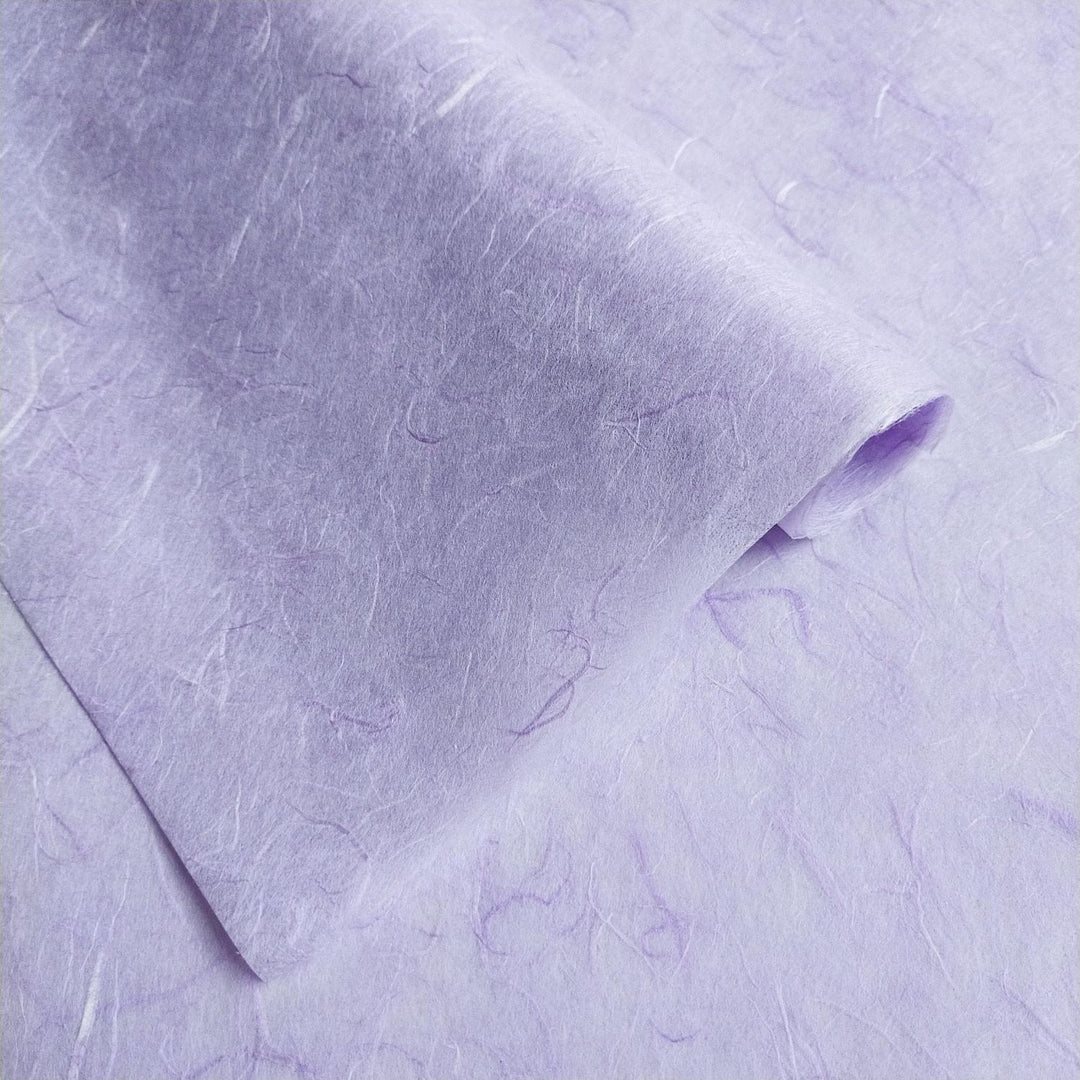 A close-up of a sheet of Kozo Studios Unryu Kozo Paper in Heather Purple shows textured fibers, giving it a tactile, handmade look. One edge is slightly curled.