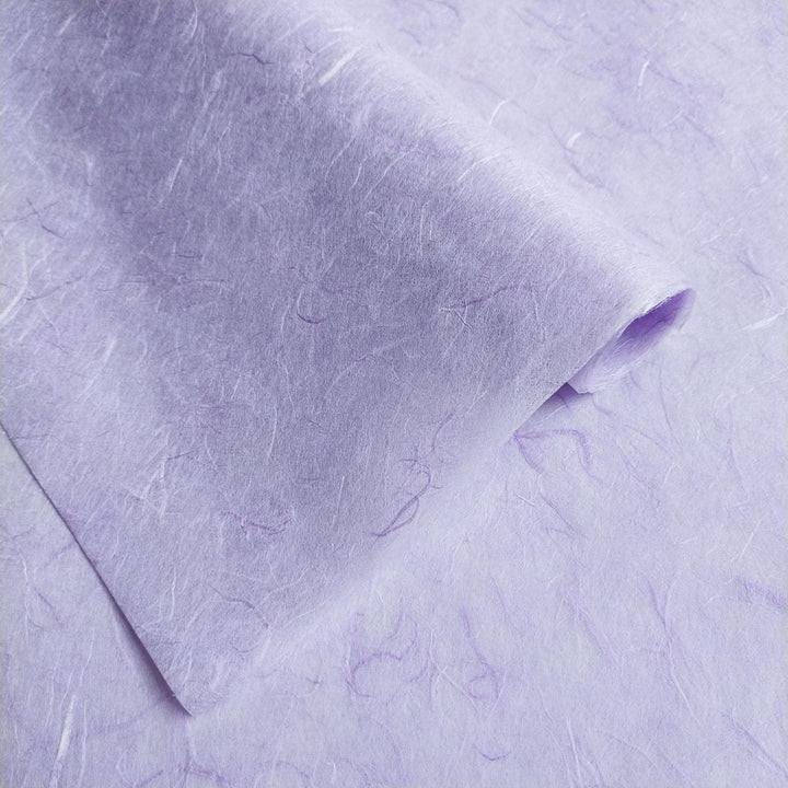 A close-up of a sheet of Kozo Studios Unryu Kozo Paper in Heather Purple shows textured fibers, giving it a tactile, handmade look. One edge is slightly curled.