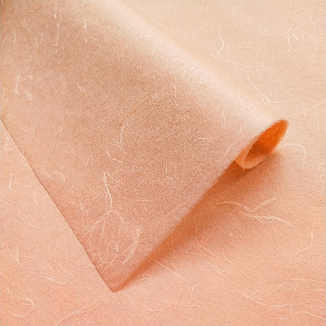 Salmon orange Unryu Kozo paper by Kozo Studio with delicate mulberry fibers and organic folds creating soft shadows.