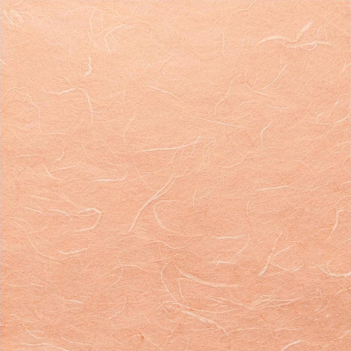 Detail of Kozo Studio mulberry paper in a warm salmon hue, highlighting handmade texture and fibrous patterns.