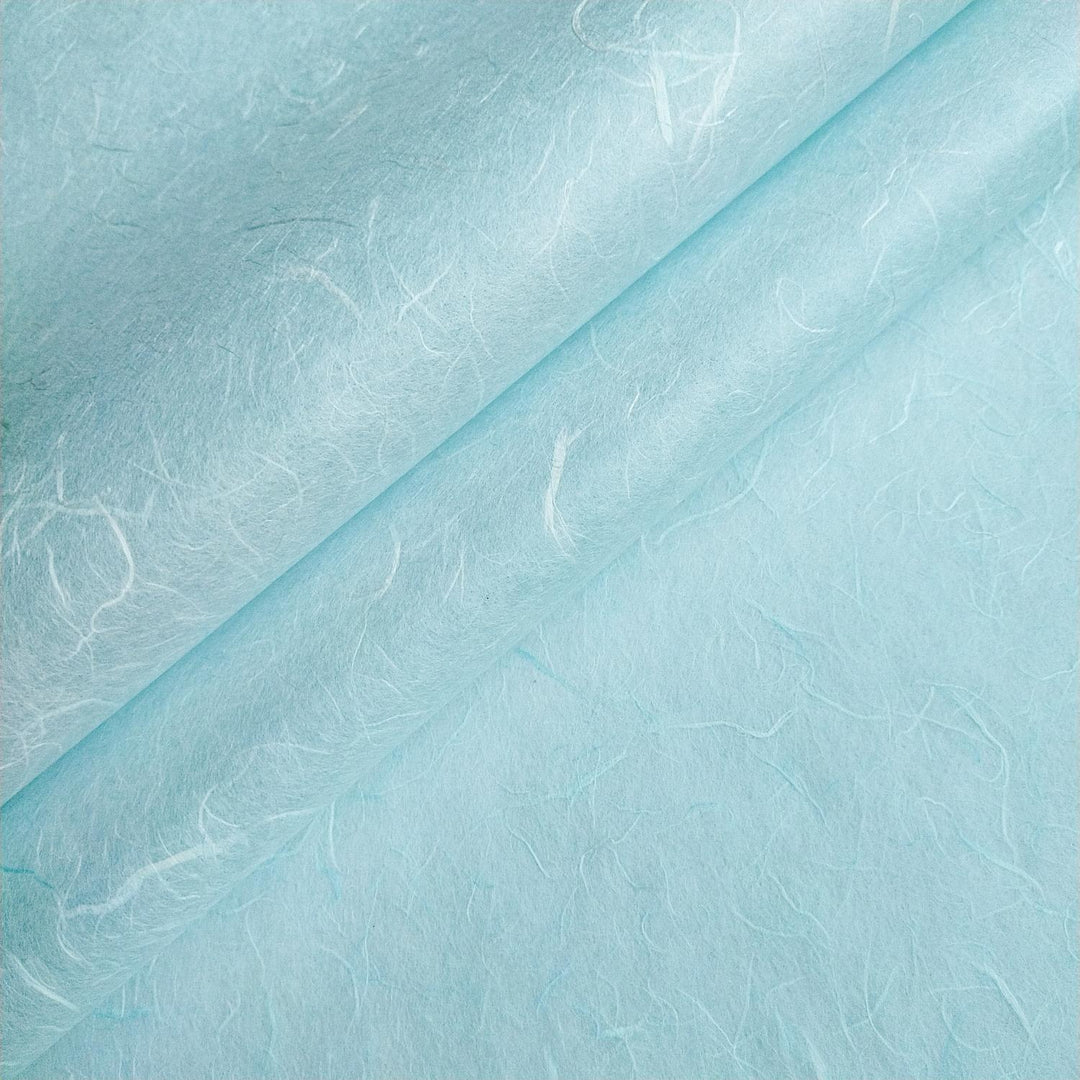 Close-up of Kozo Studio handmade paper in Sky Blue featuring textured swirls and fibrous patterns in layered mulberry paper design.