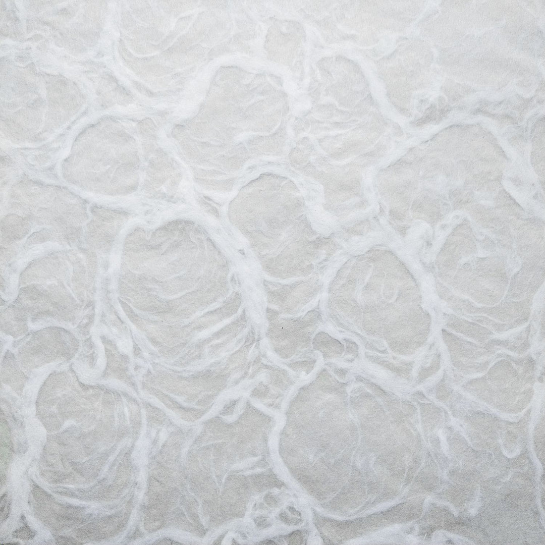 Textured white mulberry paper from Kozo Studio, captured in a detailed close-up to highlight its hand-crafted swirls and ripple-inspired design.