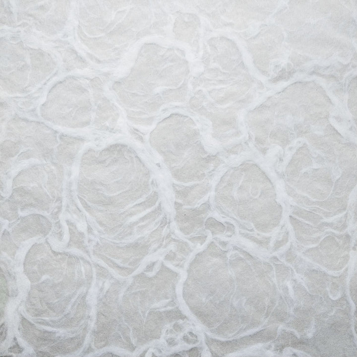 Textured white mulberry paper from Kozo Studio, captured in a detailed close-up to highlight its hand-crafted swirls and ripple-inspired design.
