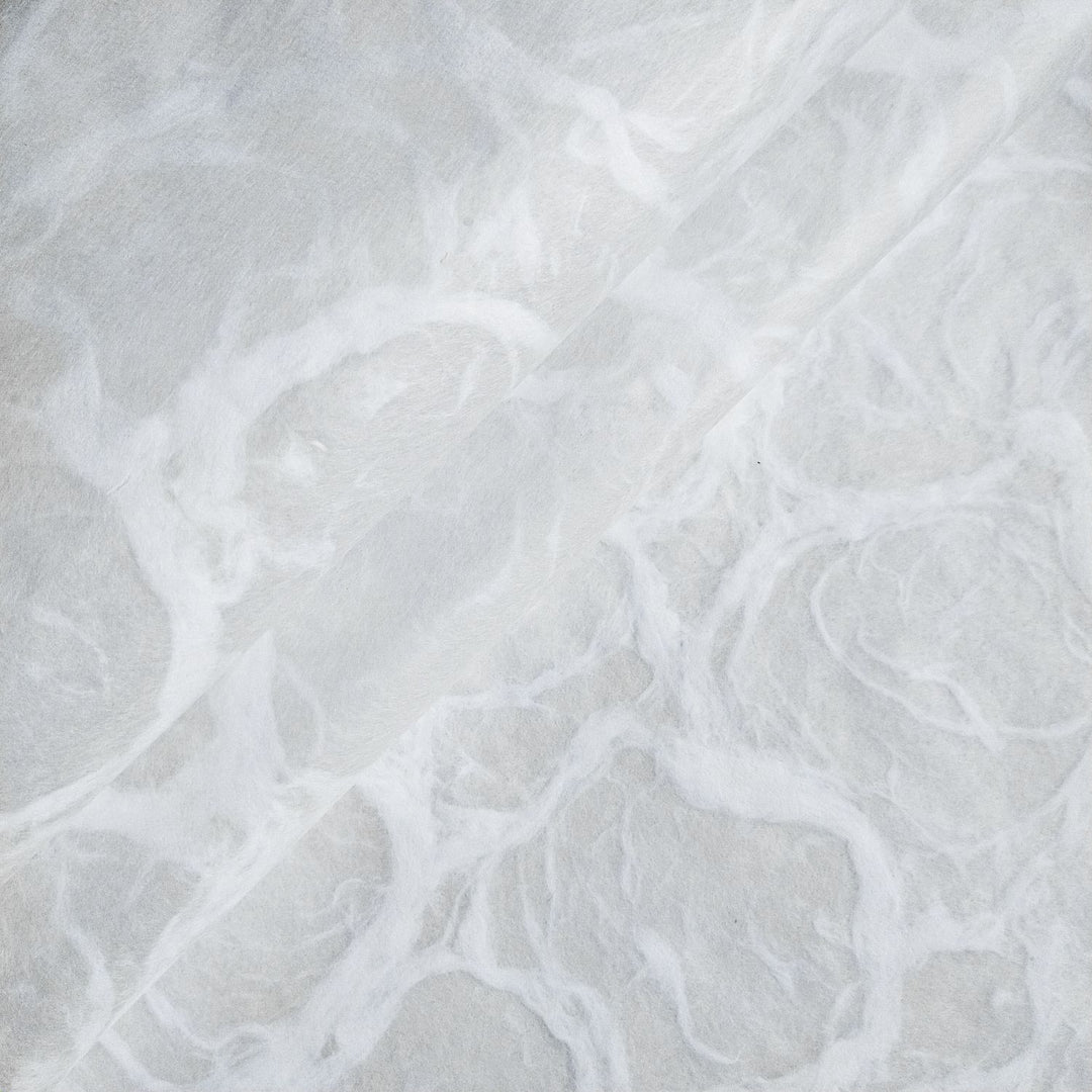 White on white handmade mulberry paper from Kozo Studio, detailed with flowing ripple patterns and a soft, fibrous texture.