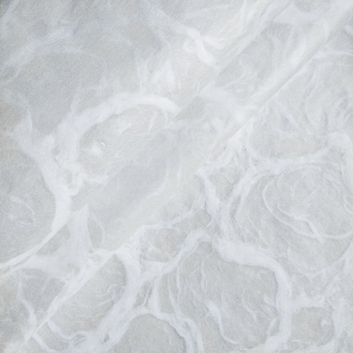 White on white handmade mulberry paper from Kozo Studio, detailed with flowing ripple patterns and a soft, fibrous texture.