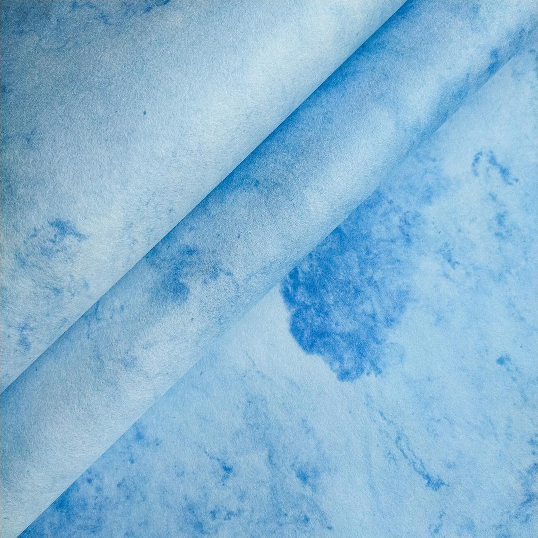 Artistic close-up of Kozo Studio mulberry paper showcasing handmade sky-blue textures with subtle marbling and a natural fold at the center.