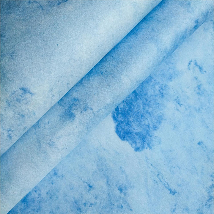 Artistic close-up of Kozo Studio mulberry paper showcasing handmade sky-blue textures with subtle marbling and a natural fold at the center.