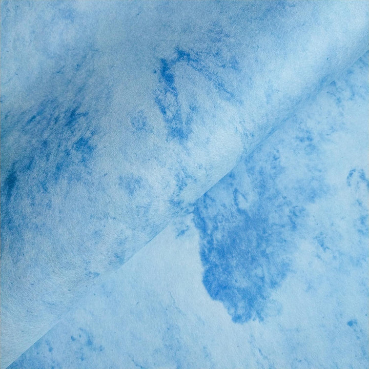 Close-up of Sky Kozo Paper Design 1 by Kozo Studio featuring marbled sky-blue handmade paper with delicate white swirls and a soft fold in the center.