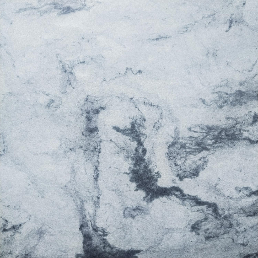 Elegant marbled mulberry paper by Kozo Studio with swirling grey and white patterns, perfect for crafts and artistic expressions.