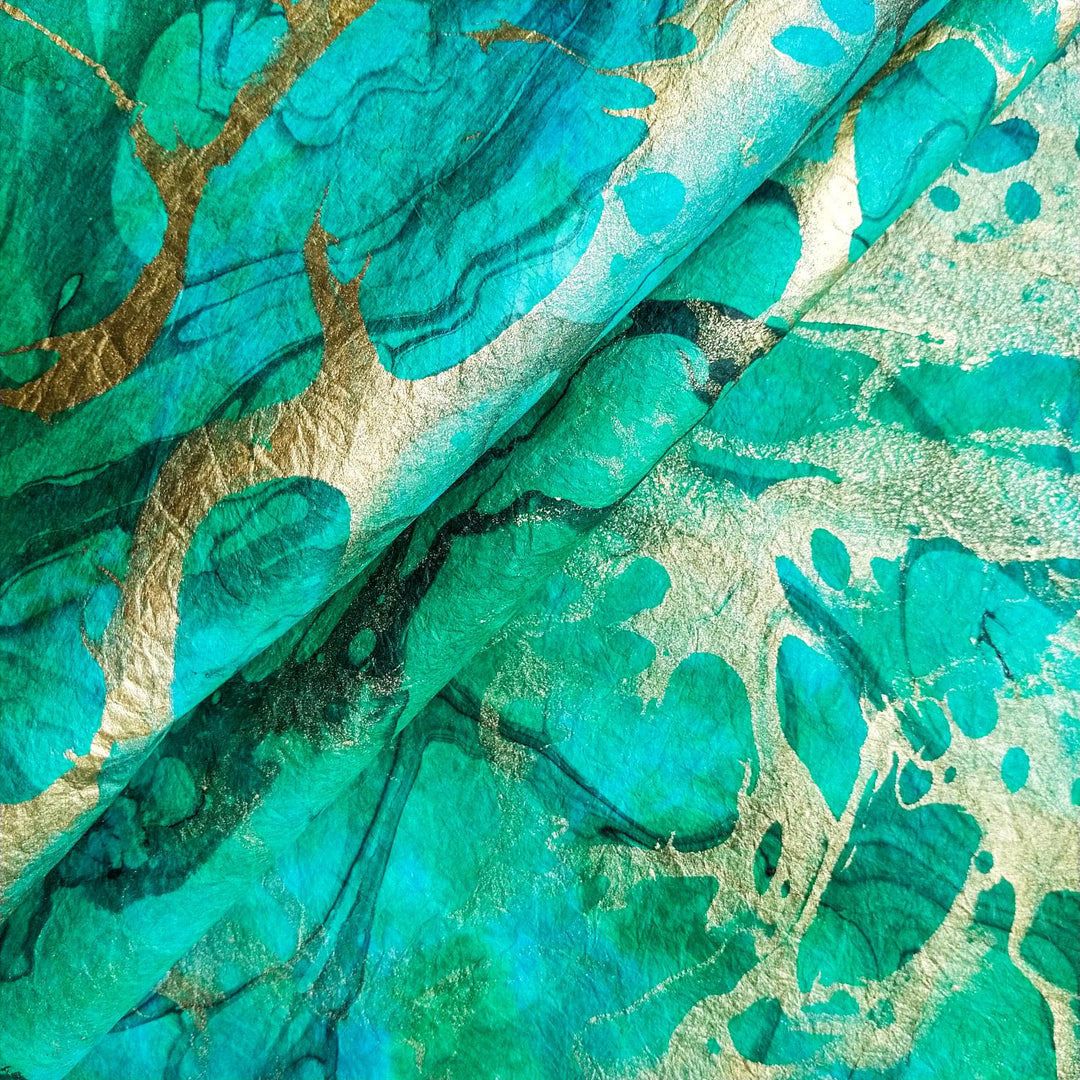 Marbled handmade paper from Kozo Studio with flowing patterns layered in vibrant oil tones on textured mulberry paper, ideal for artistic designs.