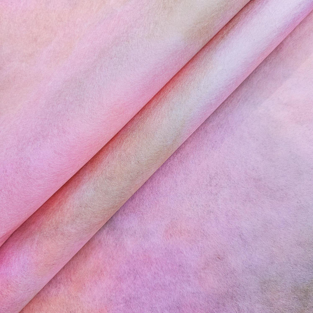 The Ombre Kozo Paper (#2 Pink Haze) by Kozo Studio features a soft, textured surface in pink and light brown hues of a delicate mulberry paper. It displays a diagonal fold that seamlessly blends colors for an abstract and gentle look.