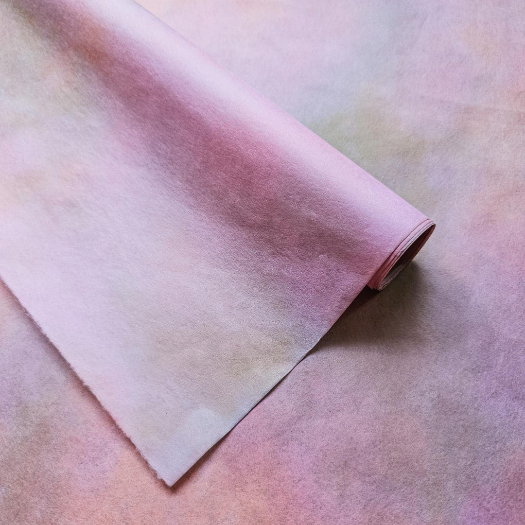 A close-up of Kozo Studio's Ombre handmade paper reveals subtle color blending in pink and tan hues, made from high-quality mulberry paper ideal for creative design projects.