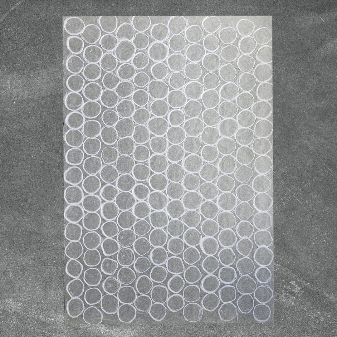 Textured white Kozo Studio mulberry paper with overlapping circular designs and organic patterns, ideal for lampshades, window coverings, and craft projects.