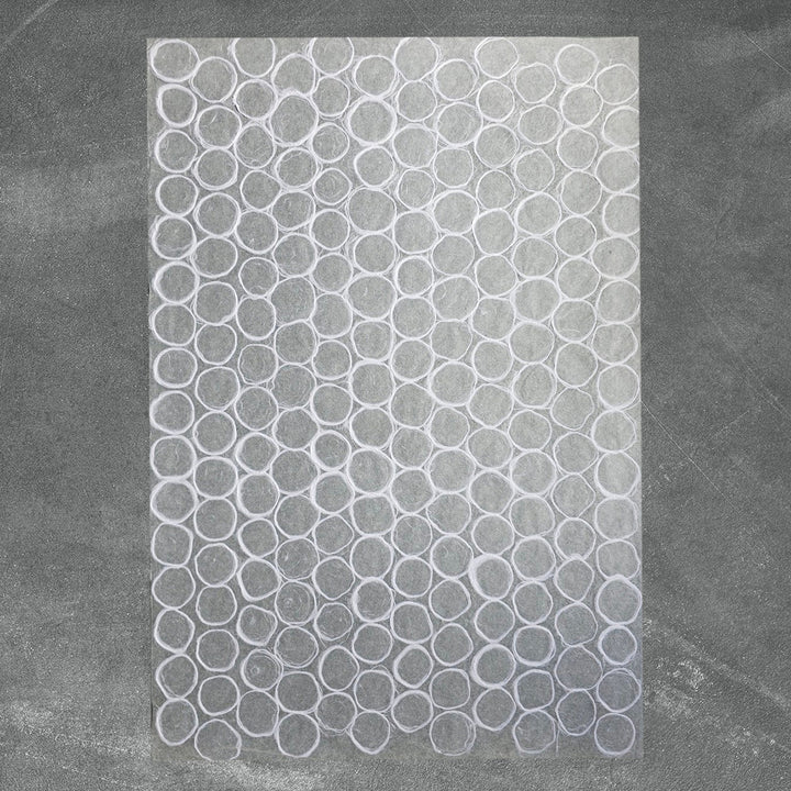 Textured white Kozo Studio mulberry paper with overlapping circular designs and organic patterns, ideal for lampshades, window coverings, and craft projects.