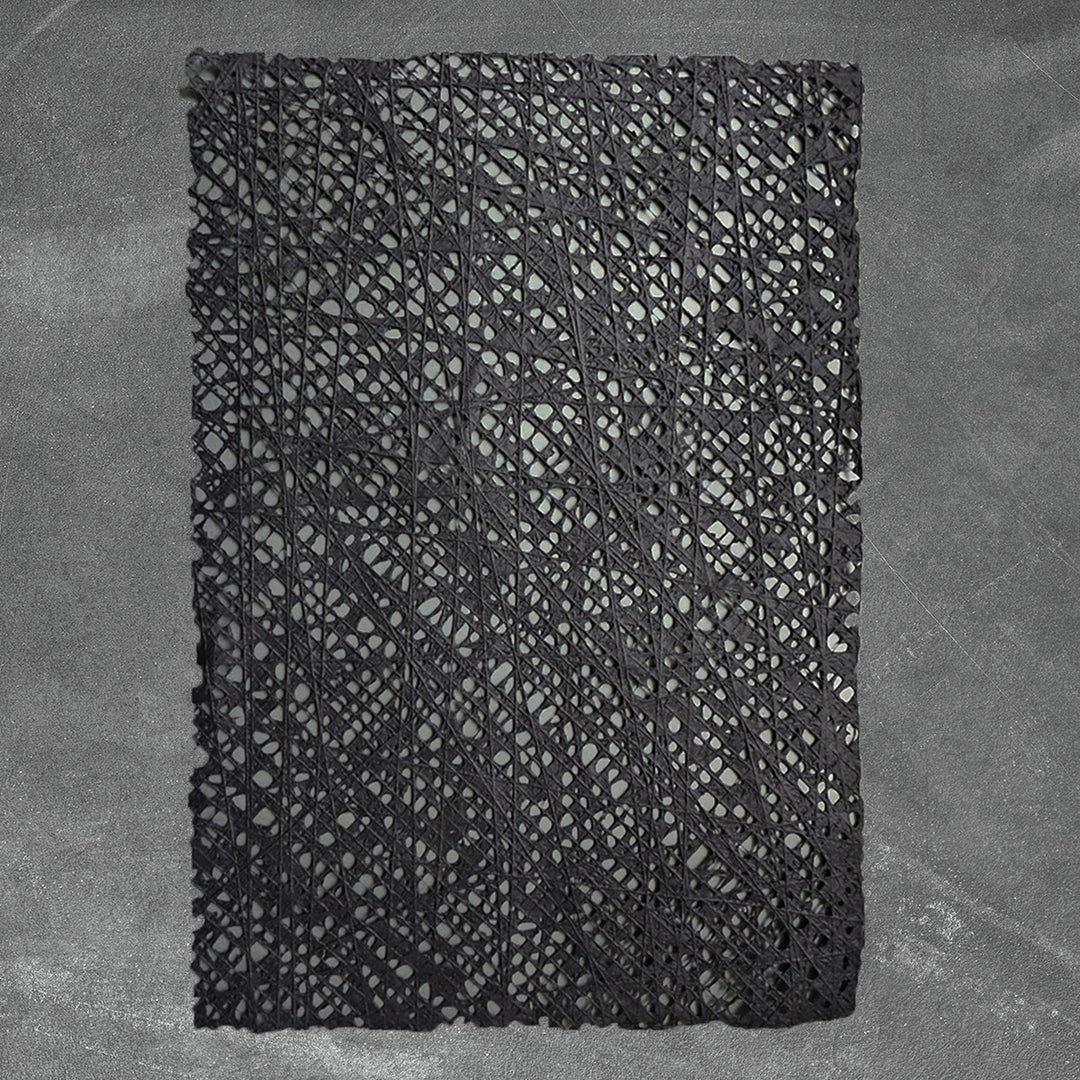 Kozo Studio's handmade paper sheet in black, showcasing a unique fishnet pattern made from cotton threads layered over traditional mulberry pulp.