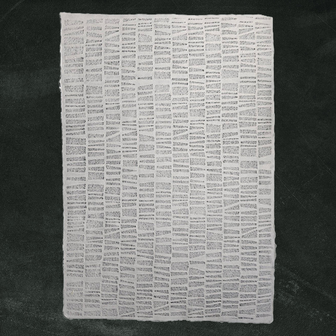 Detailed view of Kozo Studio's handmade paper featuring an Egyptian design on lace mulberry paper with a rough, brick-like texture and layered vertical and horizontal lines.