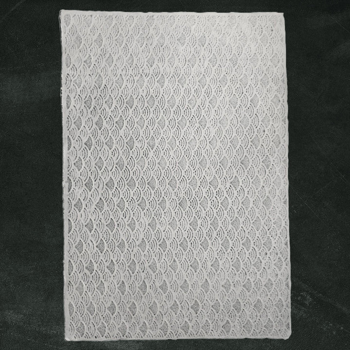 The Handmade Lace Kozo Mulberry Paper (Fan) by Kozo Studio is showcased on a dark green background, with its wavy, intricate pattern of delicate rice paper.