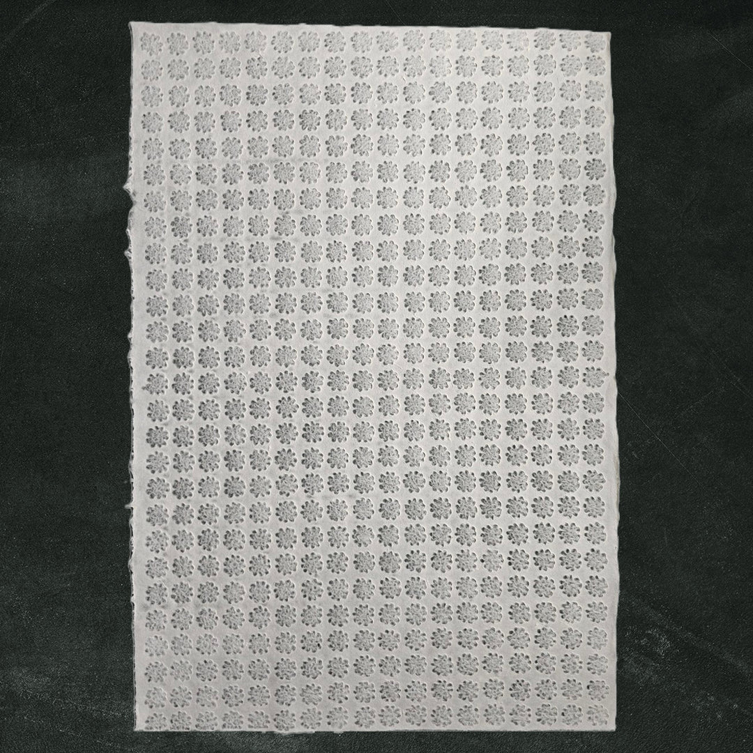 A close-up of white Handmade Kozo Paper with intricate floret designs, crafted using the Rakusui technique by Kozo Studio on premium mulberry paper.