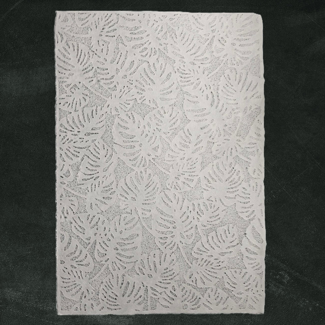 Handmade paper from Kozo Studio featuring Monstera-inspired lace design, partially rolled and elegantly crafted from mulberry paper with a soft, translucent texture.