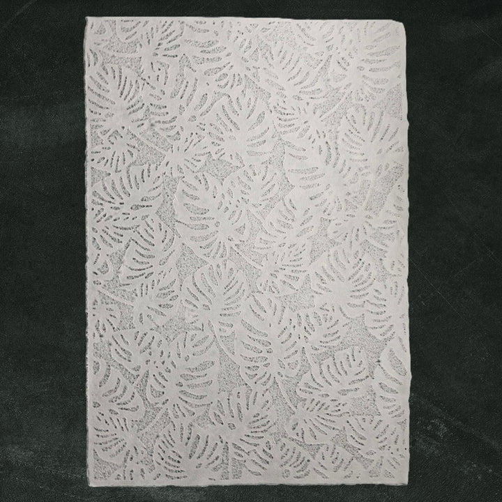 Handmade paper from Kozo Studio featuring Monstera-inspired lace design, partially rolled and elegantly crafted from mulberry paper with a soft, translucent texture.