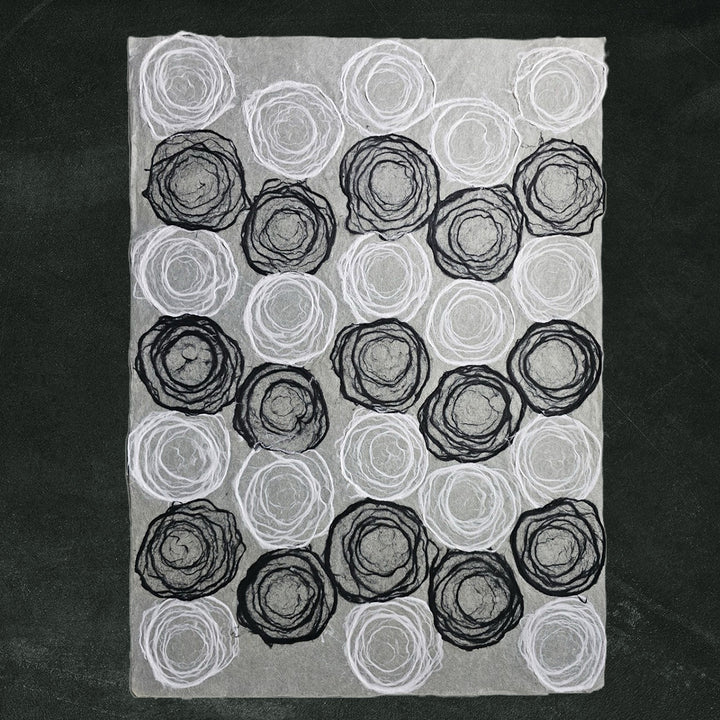 Delicate handmade paper crafted by Kozo Studio with rose-like circular pulp designs on translucent mulberry paper for creative use.