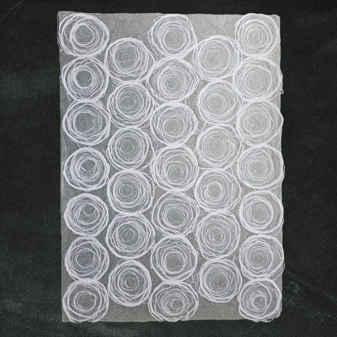 White handmade paper with circular pulp design on thin mulberry paper, created at Kozo Studio for creative and elegant uses.