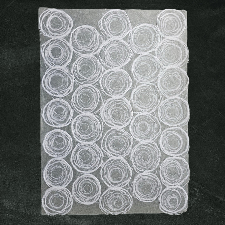 White handmade paper with circular pulp design on thin mulberry paper, created at Kozo Studio for creative and elegant uses.