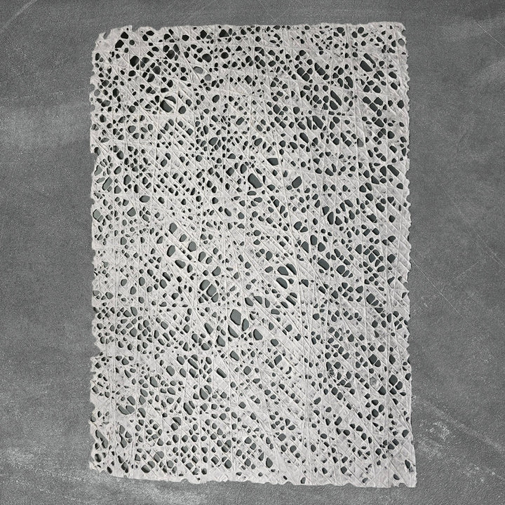 Artisanal handmade paper crafted from mulberry fibers at Kozo Studio, featuring delicate fishnet threading for fine art and decor projects.