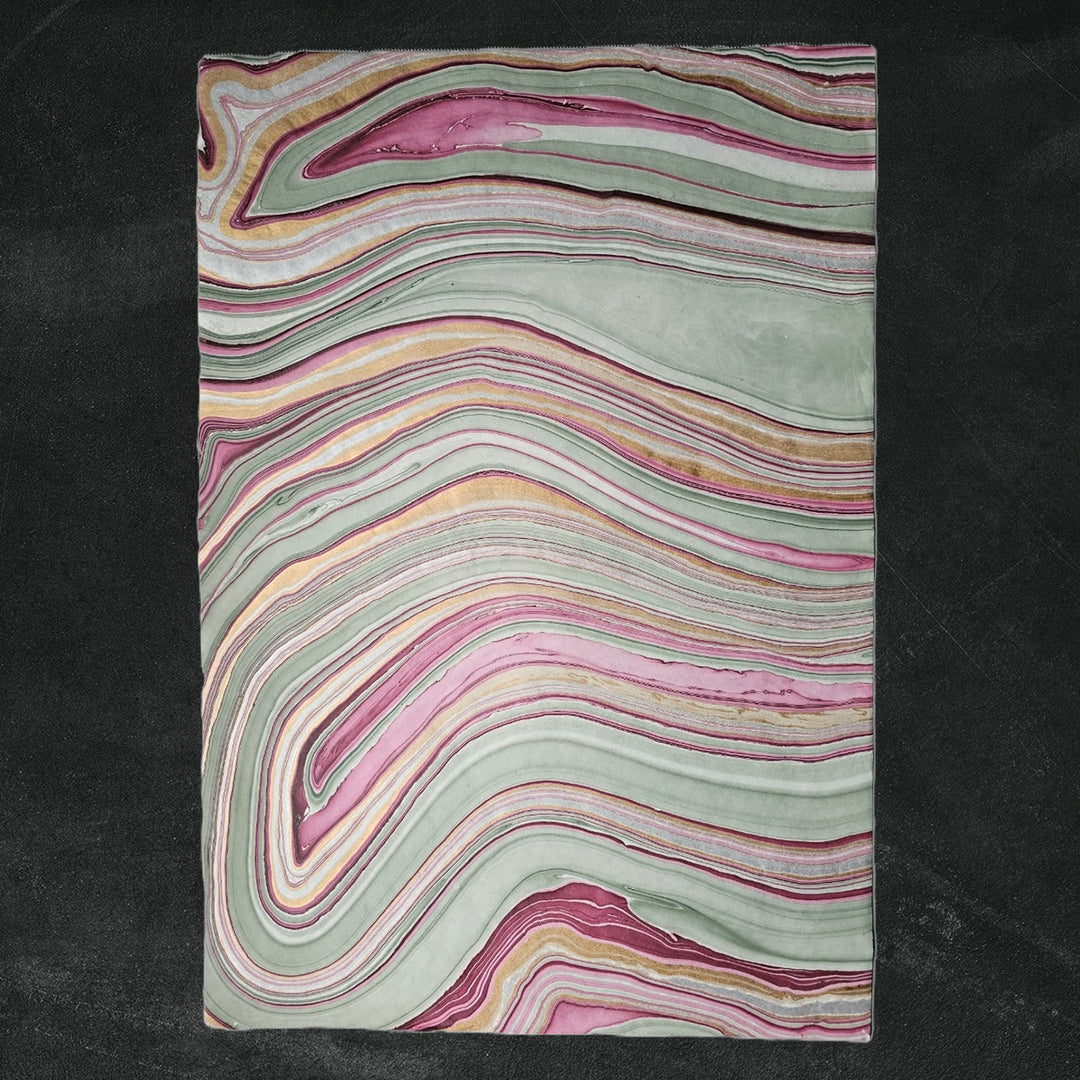 Handmade mulberry paper from Kozo Studio featuring a marbled design in soft pastel shades, with a top corner slightly curled to highlight the layered kozo paper effect.