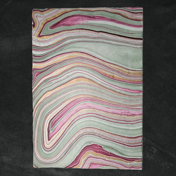 Handmade mulberry paper from Kozo Studio featuring a marbled design in soft pastel shades, with a top corner slightly curled to highlight the layered kozo paper effect.
