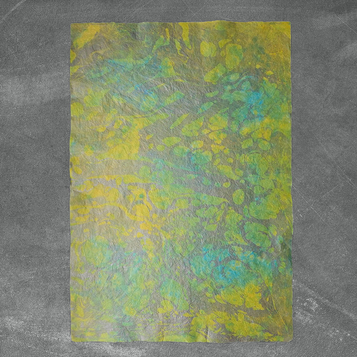Elegant handmade paper from Kozo Studio with swirling oil-based designs beneath delicate mulberry paper layers for artistic use.