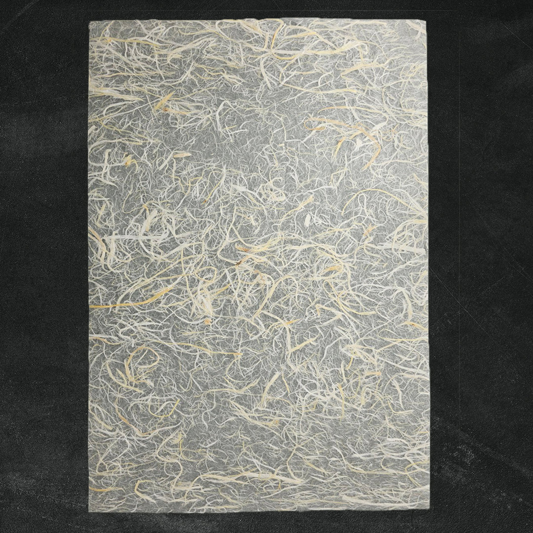 A close-up of handmade Unryu paper from Kozo Studio showing textured mulberry bark fibers embedded in a delicate kozo paper sheet, ideal for artistic and craft use.