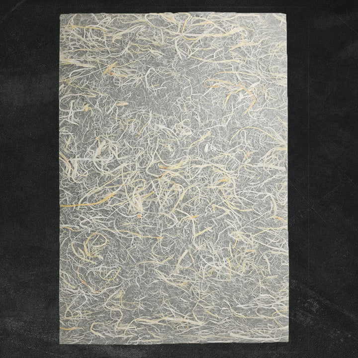 A close-up of handmade Unryu paper from Kozo Studio showing textured mulberry bark fibers embedded in a delicate kozo paper sheet, ideal for artistic and craft use.